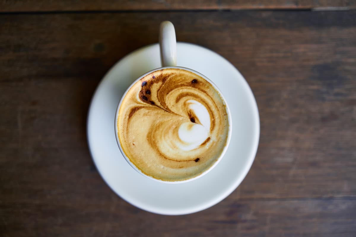 Small ceramic coffee cup with heart-shaped foam art