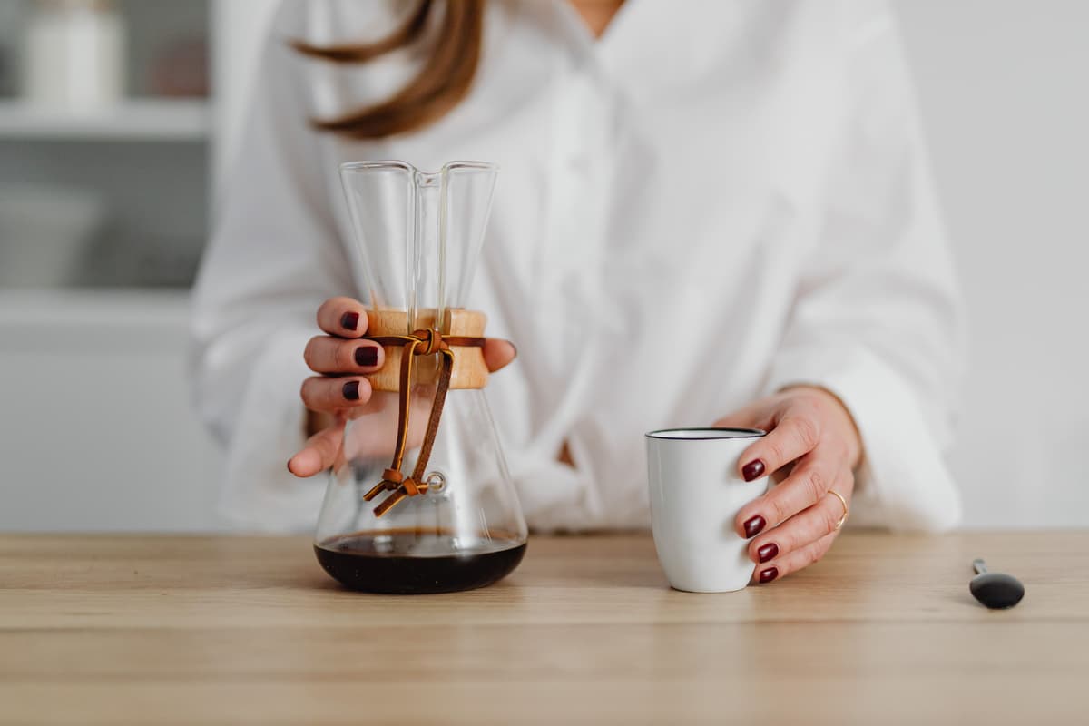 Glass carafe with freshly brewed coffee next to a ceramic mug